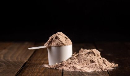 Measuring scoop of whey protein on wooden table to prepare a milkshake. Concept of diet, health and exercise