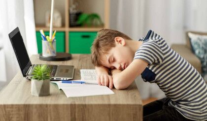 children, education and learning concept - tired student boy sleeping on desk at home