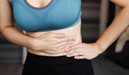 Close up of the woman holding her belly. Pain after home workout. Weight loss, slim body, healthy concept