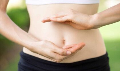 Close-up of hands of young Caucasian woman showing her slim belly. Fitness and dieting concept