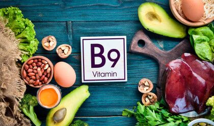 Foods that contain natural vitamin B9: Liver, avocado, broccoli, spinach, parsley, beans, nuts, on a blue background. Top view.