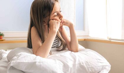 Adorable little girl with pillow in bed early in the morning, copy space.