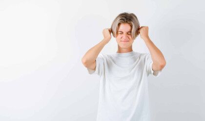 teen boy in t-shirt holding fists near head and looking annoyed , front view.