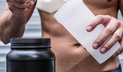 Muscular man making protein cocktail in crossfit gym