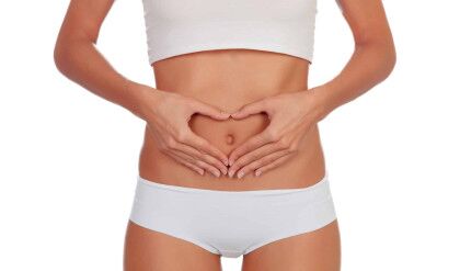 Girl in white underwear forming a heart with her hands on her belly isolated