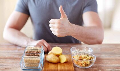 healthy eating, diet, gesture and people concept - close up of male hands showing thumbs up with carbohydrate food on table